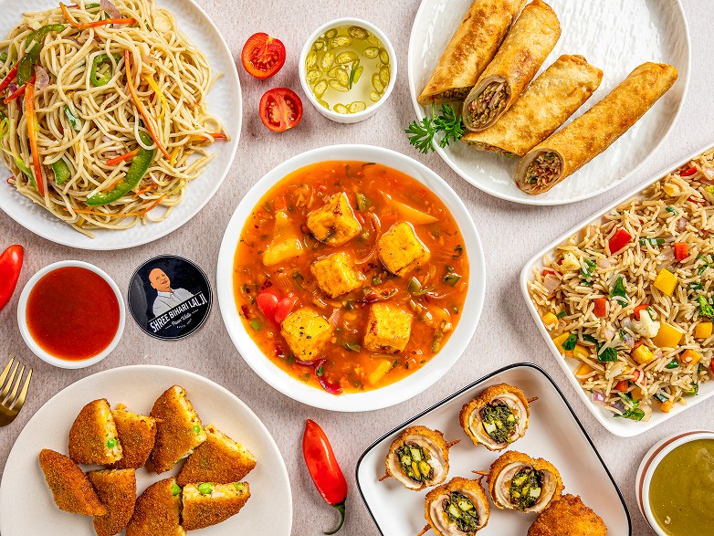 Table spread of noodles, fried rice, spring rolls and Cheese Chilly