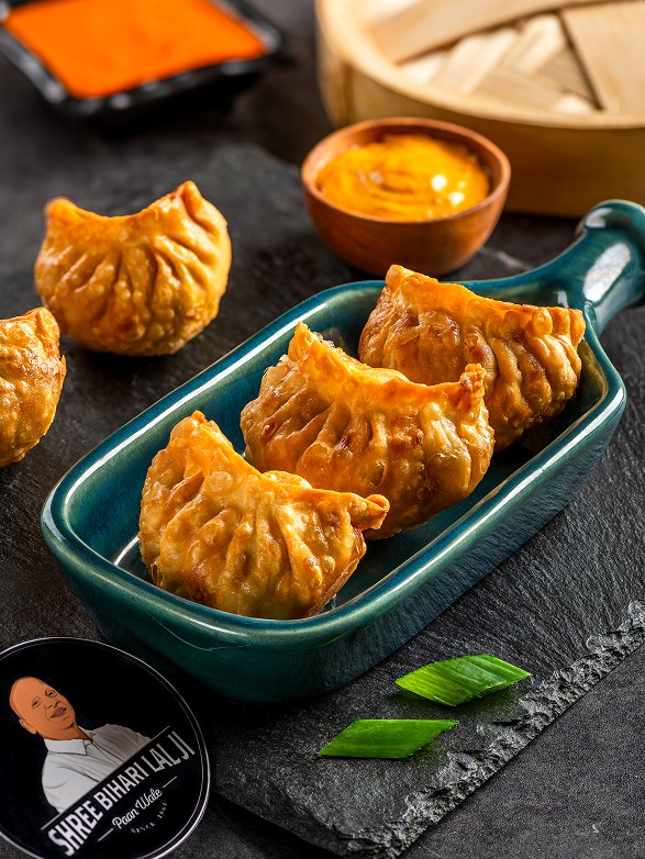 Golden fried momos on a teal dish with spicy chutney