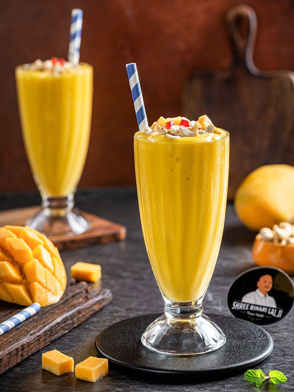 Two tall glasses of Mango Shake topped with nuts